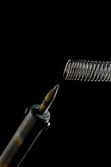 Naklejka premium heated soldering iron and solder. dark background. close-up