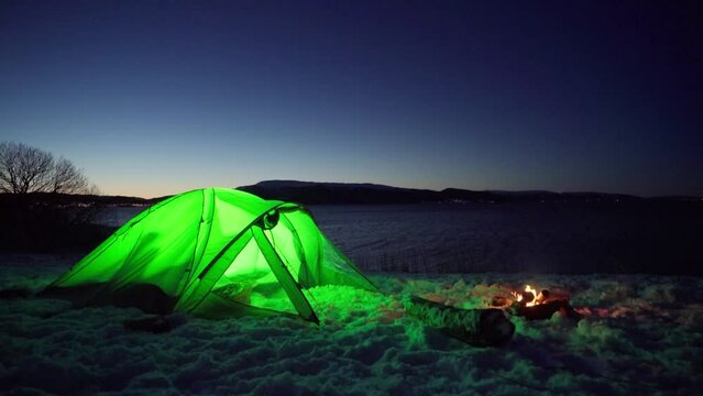 Illuminated Green Camping Tent With Camp Fire At Night. - wide shot