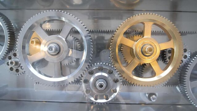 Set of silver and golden interlocked gears rotating to open a latch mechanism, Close up shot