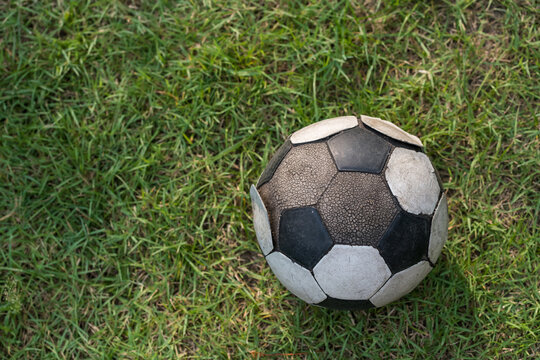 old soccer ball on football grass by top view