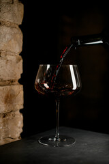 Close up perspective of wine glass filled with red wine with dark background