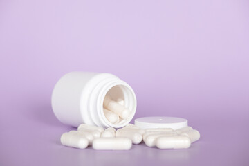 Close up white pills and capsules on purple background with copy space. Focus on foreground, soft bokeh. Pharmacy drugstore concept.