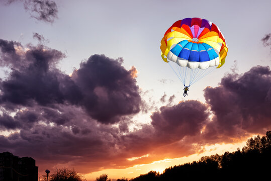 Gliding with a parachute on the background of bright sunset.