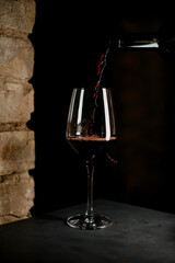 Close up perspective of dark bottle up to half crystal clear wine glass with red wine