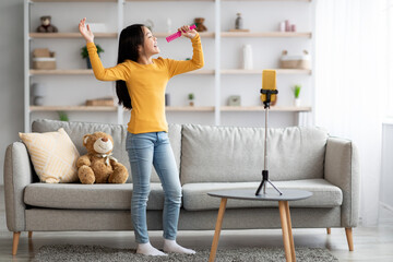 Cute asian child singing and recording video on smartphone