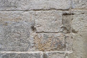 Ancient wall made of rectangular natural factured stones. Old dirty brick wall.