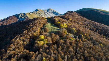 Aerial view of Monte Terminillo in Italy. Beautiful autumn landscape of the Italian central Apennine beech forest. In the background the rocky peak of the mountain. - obrazy, fototapety, plakaty