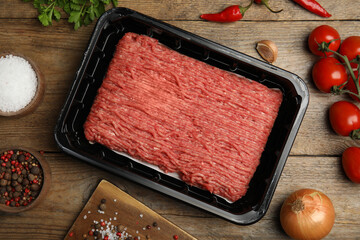 Raw fresh minced meat, tomatoes and other ingredients on wooden table, flat lay