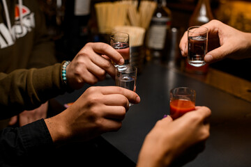 Four young people toasting with mexican tequila shots and tomato juice
