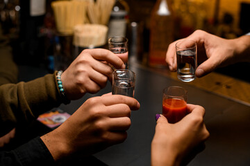 group of young people toasting with mexican tequila shots and tomato juice