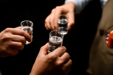 people,s hands cheers with mexican tequila shots and tomato juice on dark background