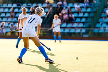Fototapeta premium Young female field hockey player with the ball on the pitch.