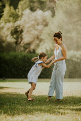 Cute little girl having fun on a grass with her mother