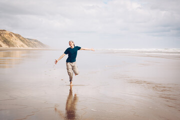 Young man with wanderlust enjoying his sabbatical holiday on the idyllic beach of New Zealand - obrazy, fototapety, plakaty
