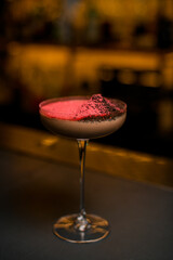 Close up photo of brown cocktail in wide low glass on a high stemp