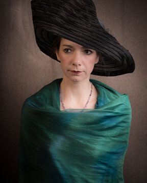 Classic dark painterly studio portrait of a woman with hat wrapped in green fabric in old masters style