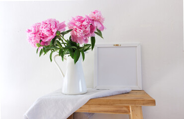 Floral composition, vase with peonies on an old wooden bench. White wall background. Scandinavian interior room design. Selective focus. Spring flowers. Spring background concept. A place for your tex