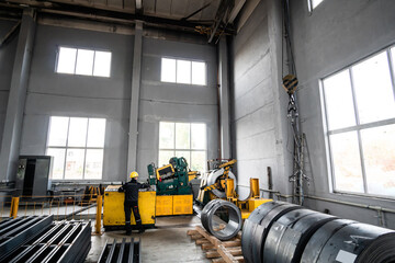 a worker in a yellow helmet operates a large machine for metal leveling