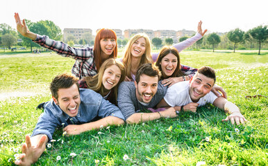 Young people having fun together with self portrait on grass meadow - Youth life style concept with happy friends at picnic camping out side - Warm vivid filter with backlight contrast sunshine - 483740123