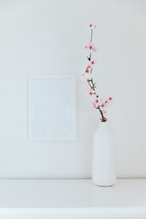 Almond blossom branches in a vase with picture frame mockup. White background, copy space.