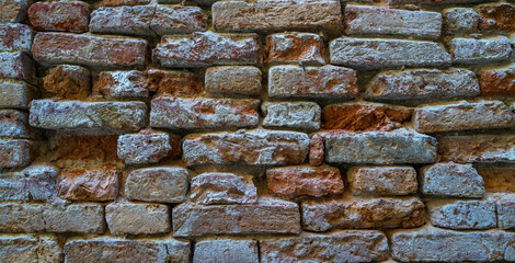 Empty old brick texture. Distressed wall surface. Wide brick wall background. Shabby building facade. Abstract web banner. Copy space. Toned image. 