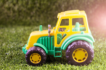 Yellow and green tractor toy on the grass in the garden