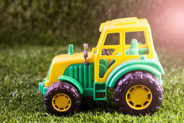 Yellow and green tractor toy on the grass in the garden