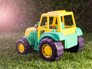Yellow and green tractor toy on the grass in the garden