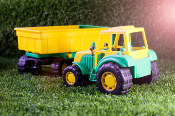Yellow tractor toy on the grass in the garden
