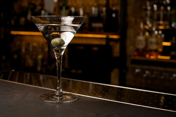 Front photo of crystal clear cocktail with olive into martini glass