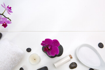 Obraz na płótnie Canvas Spa setting with pink orchids, black stones and bath salts on white wood background.