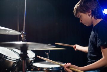 A boy plays drums in a recording studio
