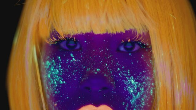 Fantasy makeup. Extreme close up portrait of young asian lady with glowing space makeup looking at camera in neon lights