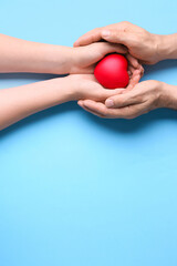 Male and female hands with red heart on blue background. Donation concept