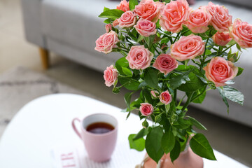 Vase with bouquet of beautiful fresh roses on table in room, closeup