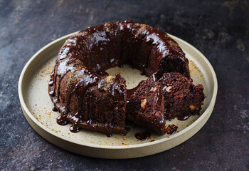 Traditional chocolate bundt cake with icing glaze topping and muscovado brown sugar served as close-up on a plate with copy space