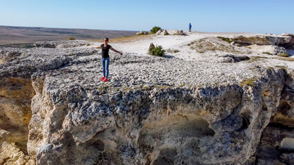 Fototapeta premium Girl poses standing at the edge on top of the White Rock Ak Kaya on the Crimea.