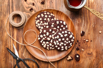 Plate of tasty cookies with white chocolate chips, rope and scissors on wooden background