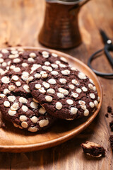 Plate of tasty cookies with white chocolate chips on wooden background, closeup
