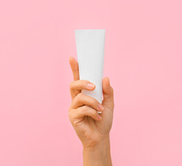 Female hand with tooth paste on pink background