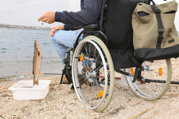 Fototapeta premium Man in wheelchair fishing on river