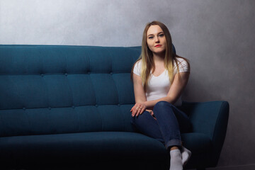 Attractive adult housewife woman sitting on the couch and looking at the camera in her house