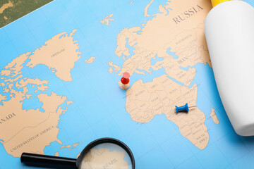 Magnifying glass, sunscreen bottle on world map, closeup