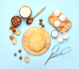 Wooden board of fresh dough for preparing walnut shaped cookies with boiled condensed milk and ingredients on blue background