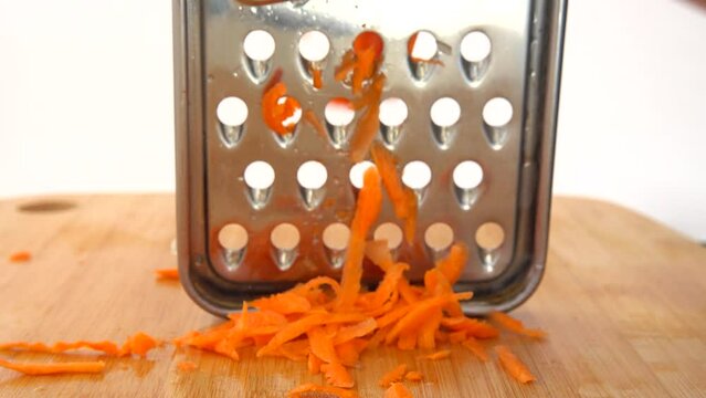 The cook cuts carrots on a grater.