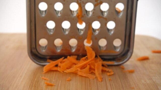 The cook cuts carrots on a grater.