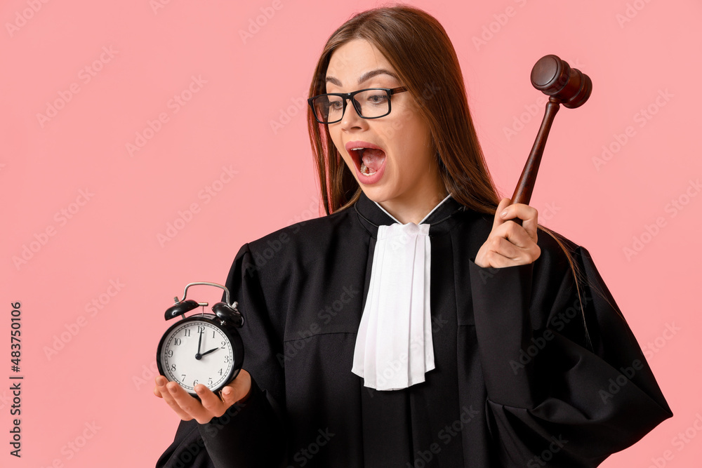 Wall mural young female judge with gavel and alarm clock on color background