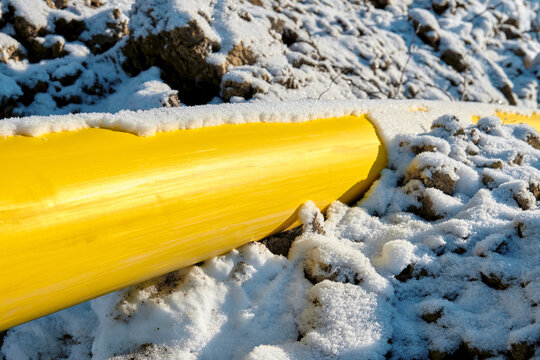 The yellow gas pipe is covered with snow.