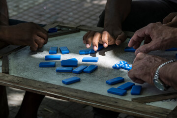 Hands picking up dominoes to play on the board.