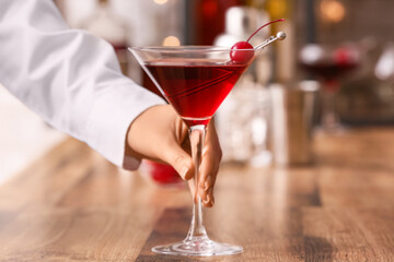 Woman with glass of tasty Manhattan cocktail on wooden table